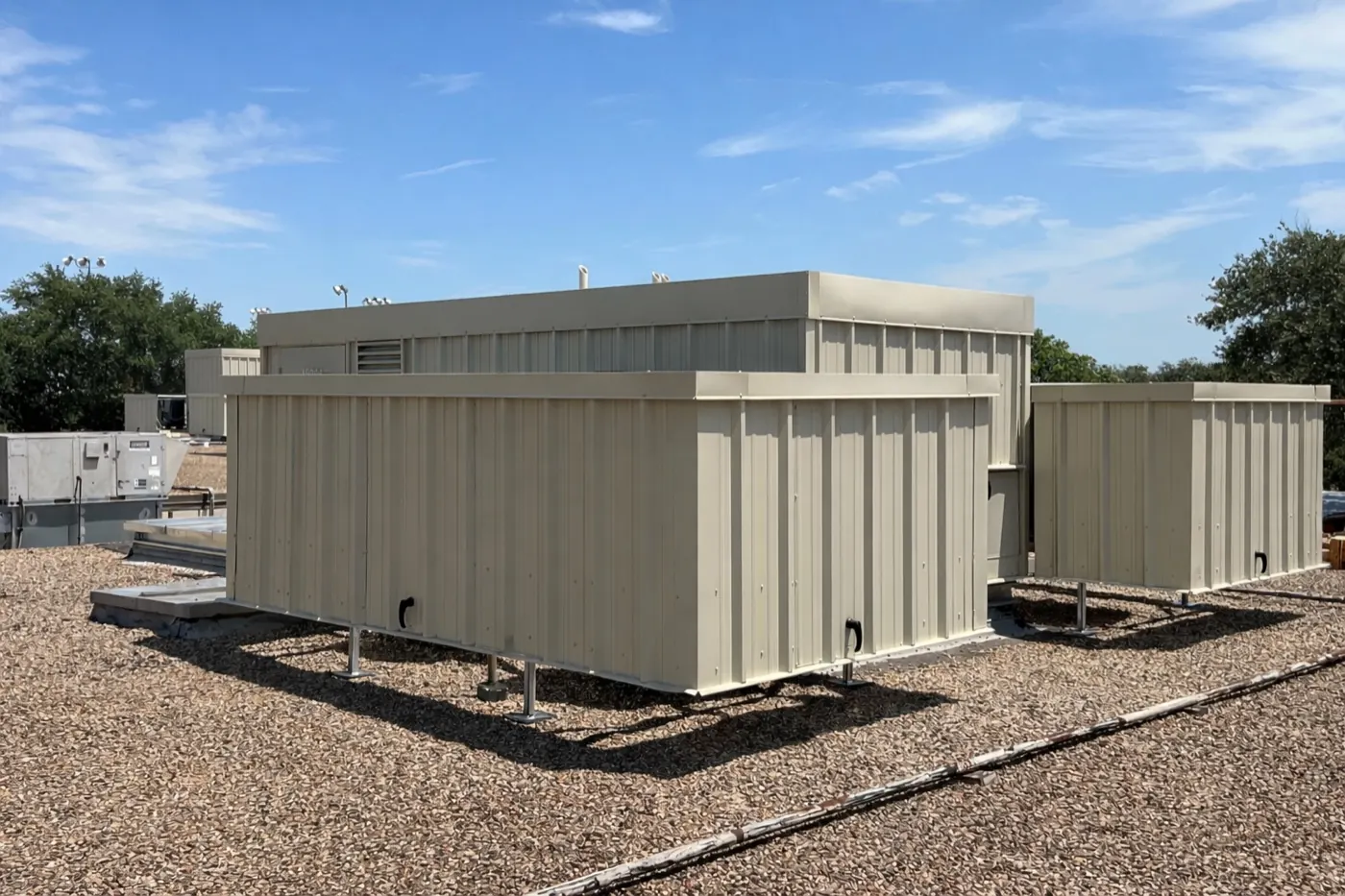Beige solid-panel HVAC screen enclosures on a gravel commercial roof