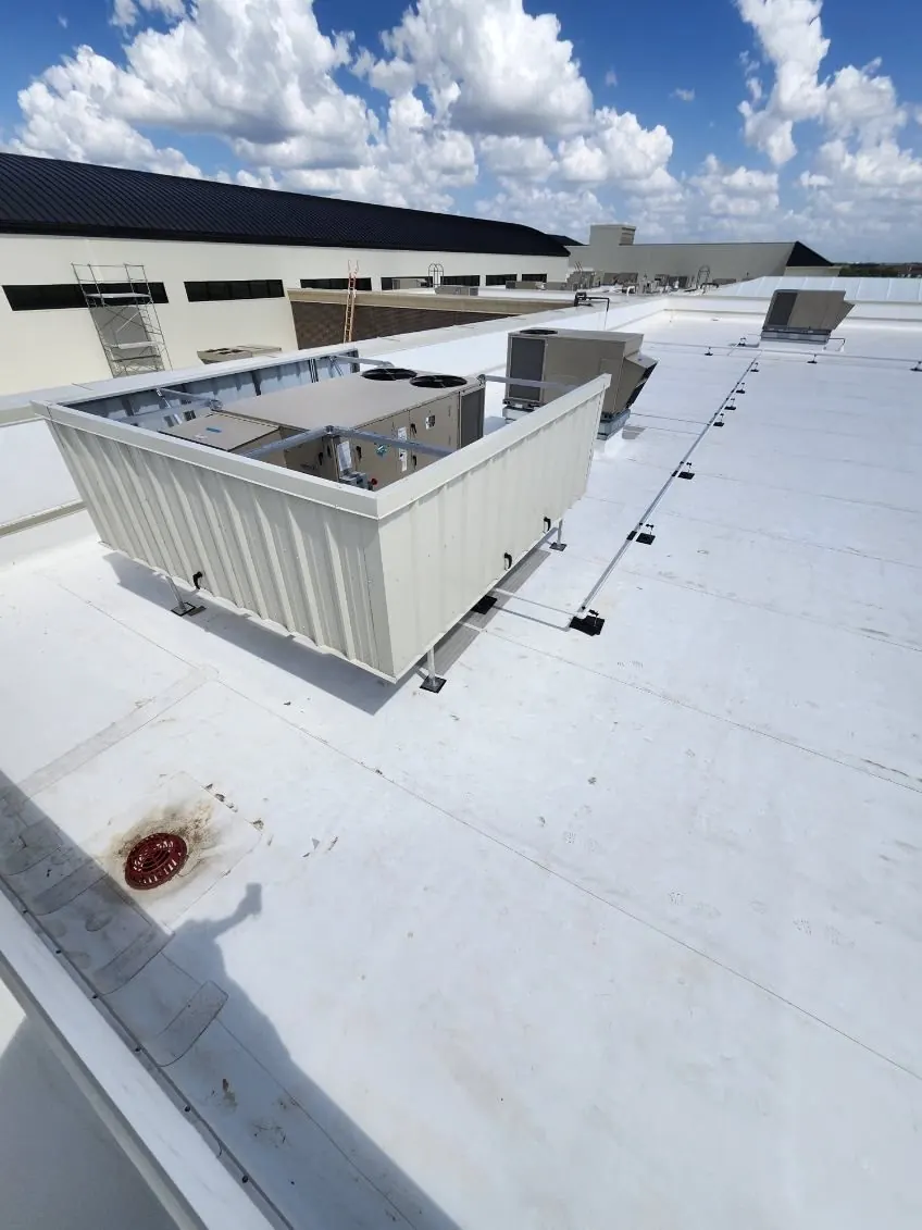 Beige corrugated screen wall concealing a rooftop HVAC unit, with the unit top visible above the screen